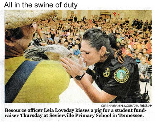 All in the swine of duty: Resource officer Leia Loveday kisses a pig for a student fund-raiser at Sevierville Primary School in Tennessee (Curt Habraken / Mountain Press / AP)