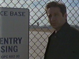 Here's Mulder standing next to a sign which reads 'No Entry No Trespassing.' He will later ignore that sign to sneak onto the base.