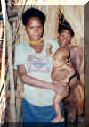 Young Mother with baby.  The women and children all sleep on one side of the grass curtain you see behind her and the men sleep on the other.