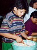 A SAMPLE student enthusiastically stirs some potato salad while making lunch for the homeless.