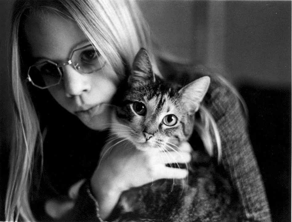 Young woman holding her cat: The cat is looking at the camera while the young woman looks away from the camera as the July sun begins to set.