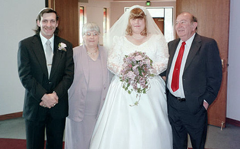 Debi's parents posing for a picture with us at our wedding